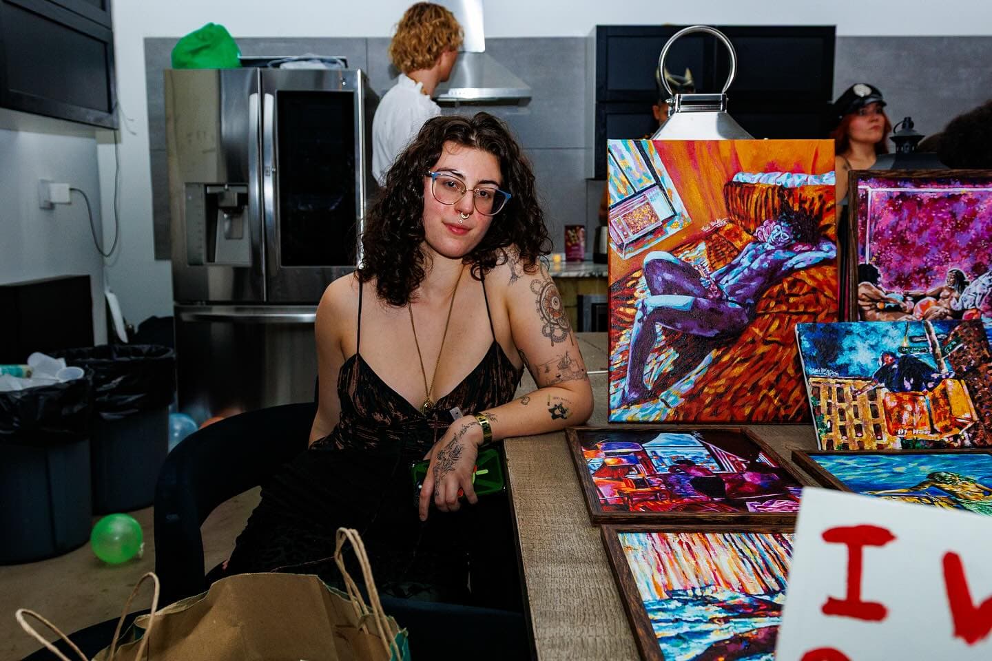 Toni Mueller seated beside a colorful group of her paintings