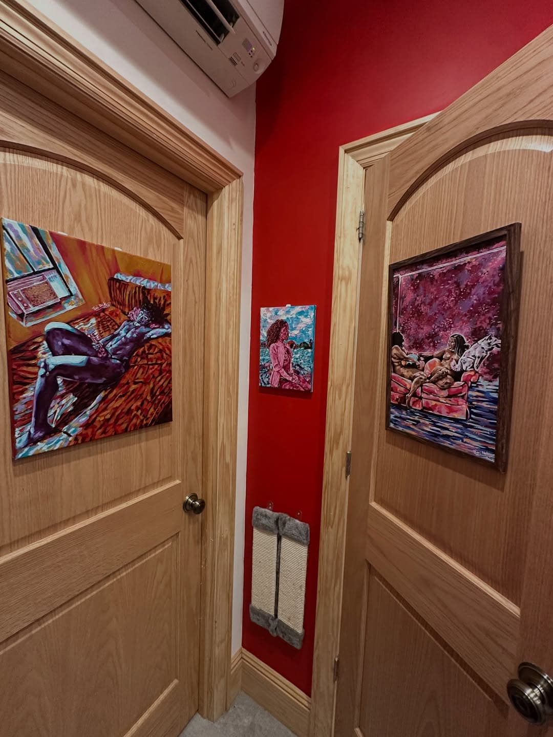 Three Toni Mueller paintings displayed in a vivid red interior